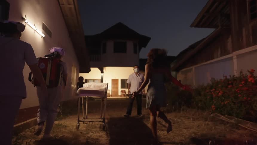 Barefoot woman runs through yard toward house door paralleled by emt reaching empty stretcher when man wearing face mask blocks hers
