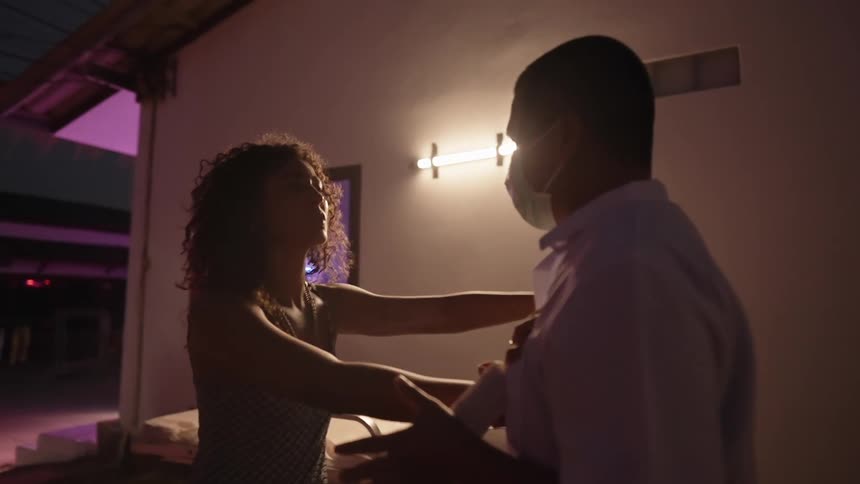 A man and woman are dancing together in a room full of flashing lights