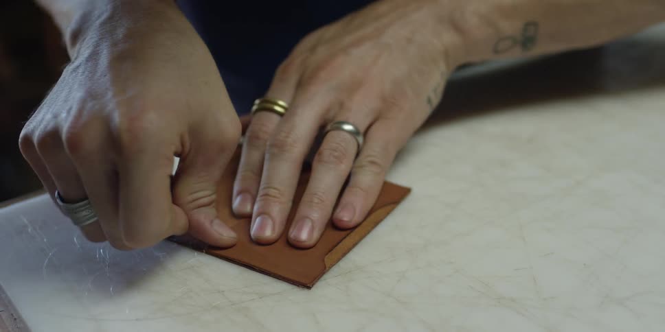 A man is working folding leather on a table