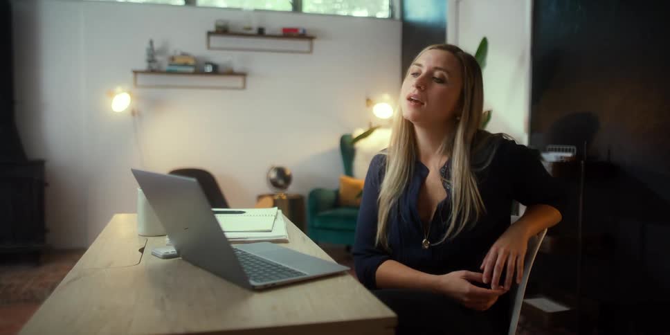 A woman nods her head as she speaks to someone on her laptop