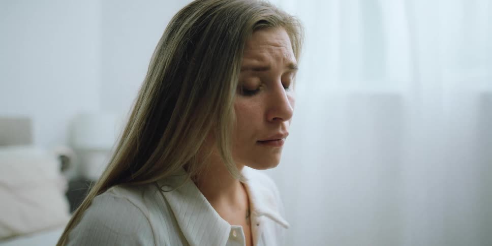A woman sitting in a room and crying
