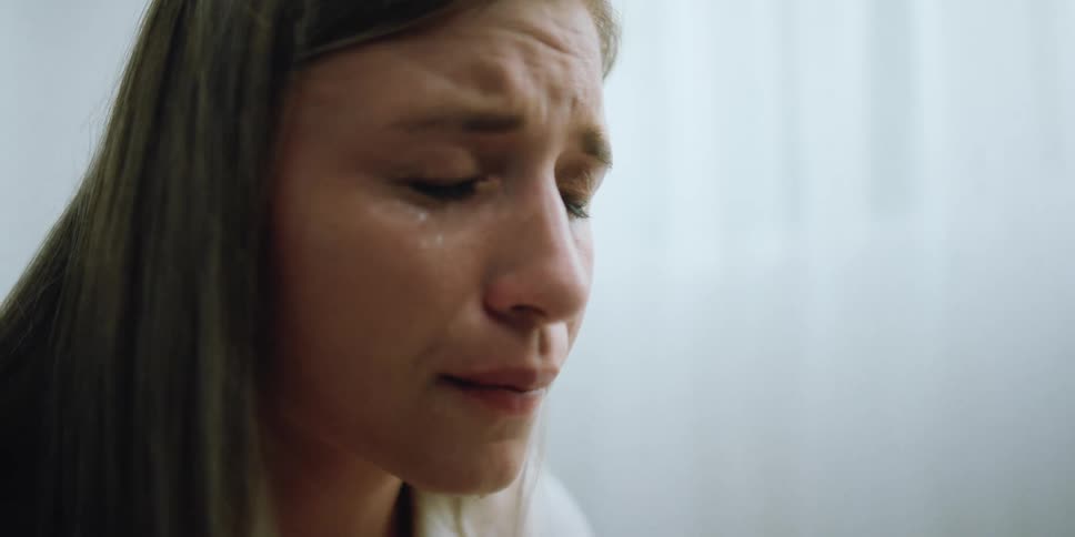 A woman cries with tears dripping from her face