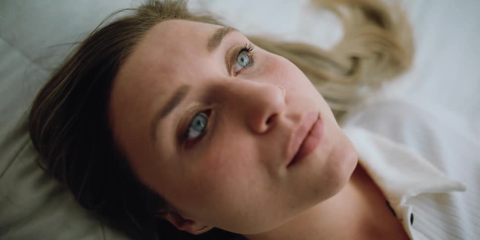 Face of a young blonde woman resting over the bed at home