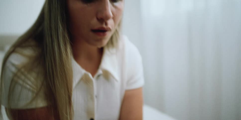 A woman is sitting on the bed sobbing