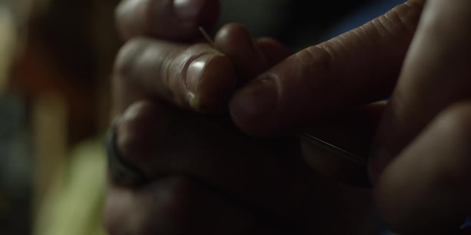 A person threads a needle