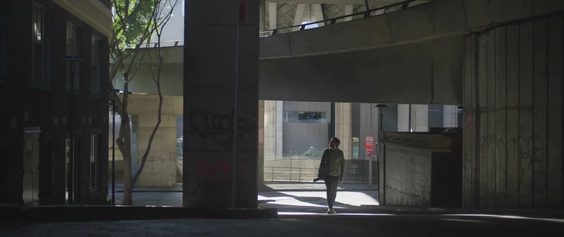 Photographer carrying a camera walks under an overpass in the city