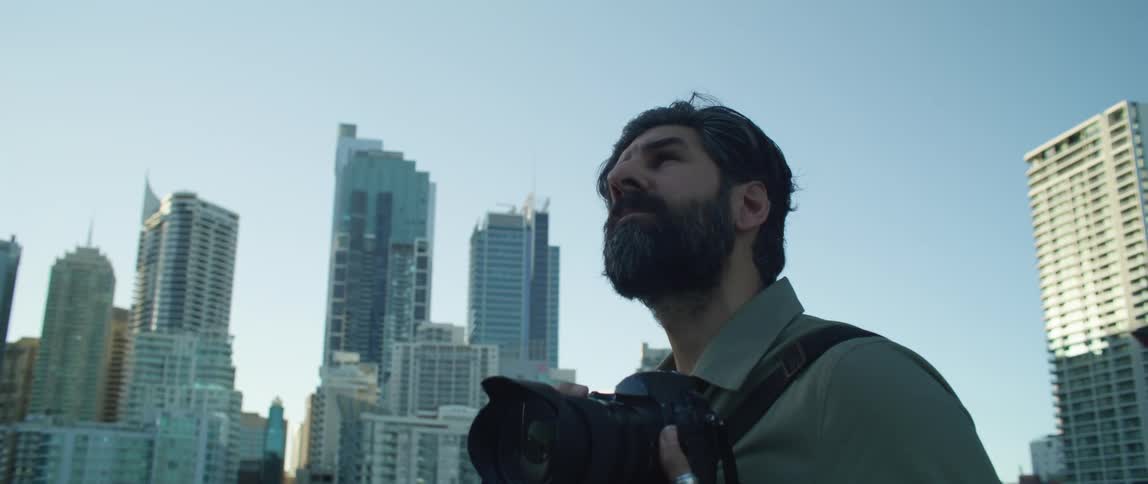 Bearded photographer takes pictures of the city skyline at sunset