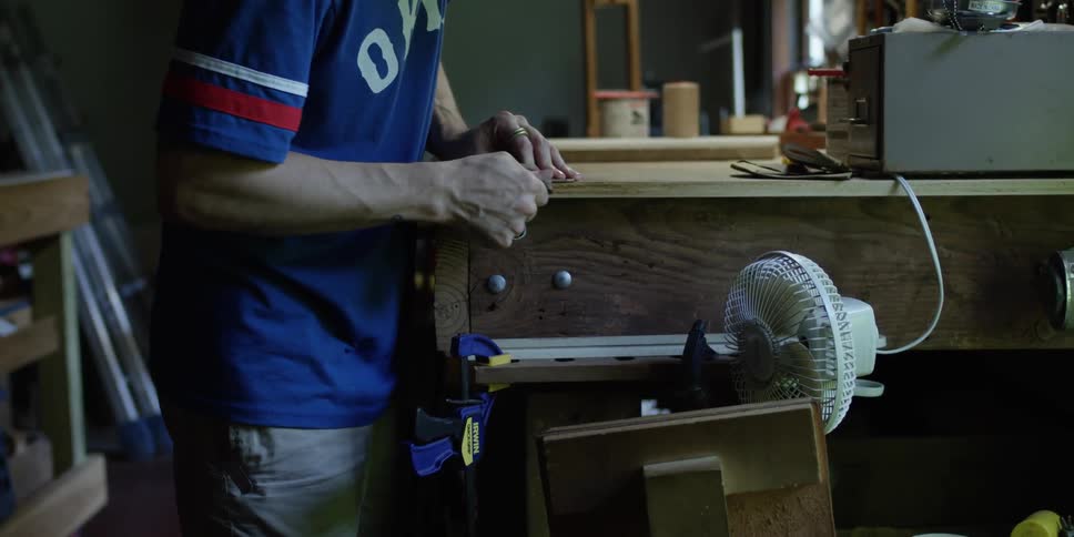 A man is working on a bench sanding something