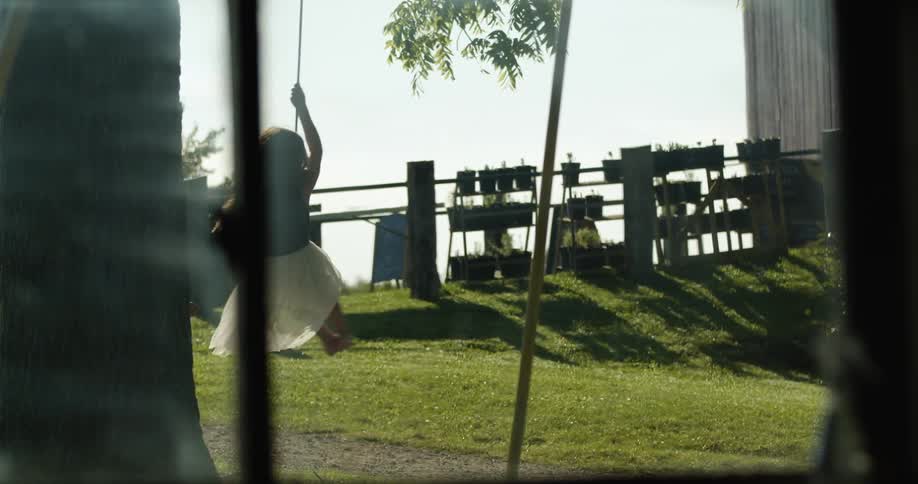 Two young girls playing on a swing hanging from a tree in the backyard at morning