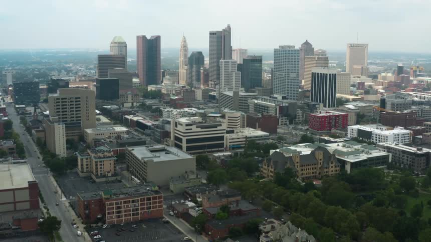 An aerial view of buildings in a city with cars driving on streets