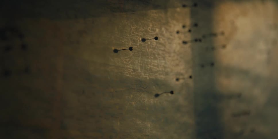 Pins over a map hanging on the wall inside a dimly lit room