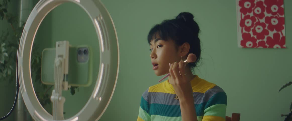 A woman records a makeup tutorial on a smart phone with special lighting