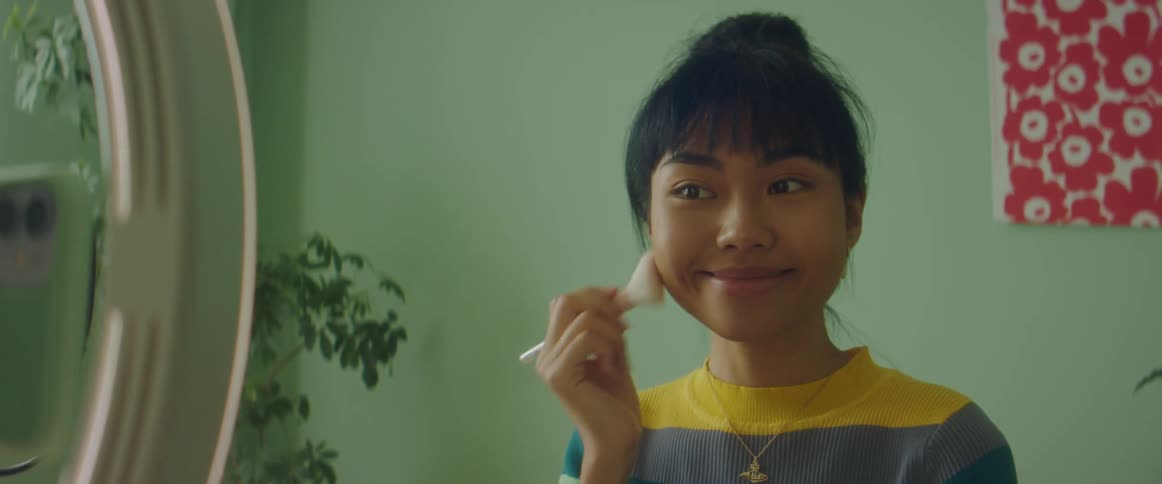 A woman filming herself applying cosmetics with a makeup brush