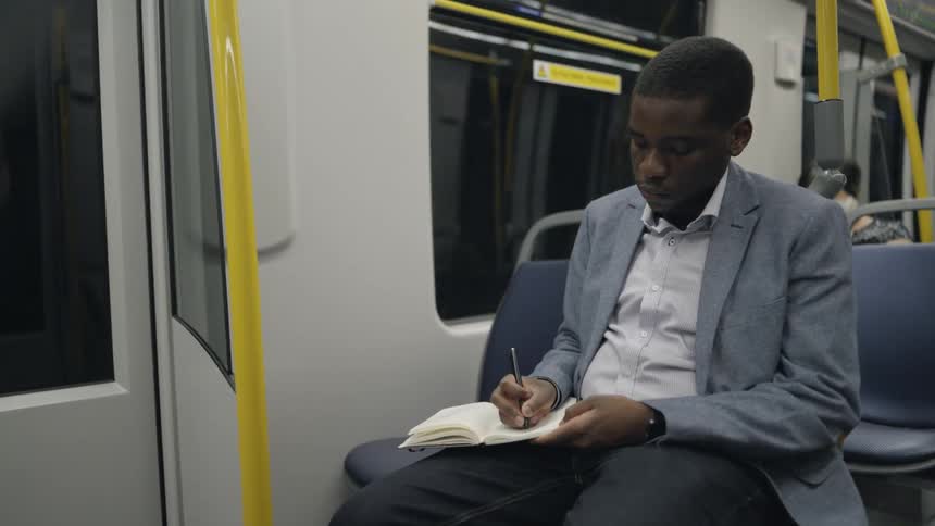 A man is writing in his notebook on the train