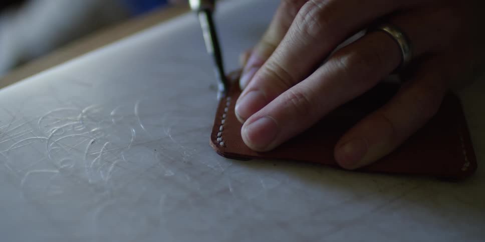 Man working on a piece of leather with a tool