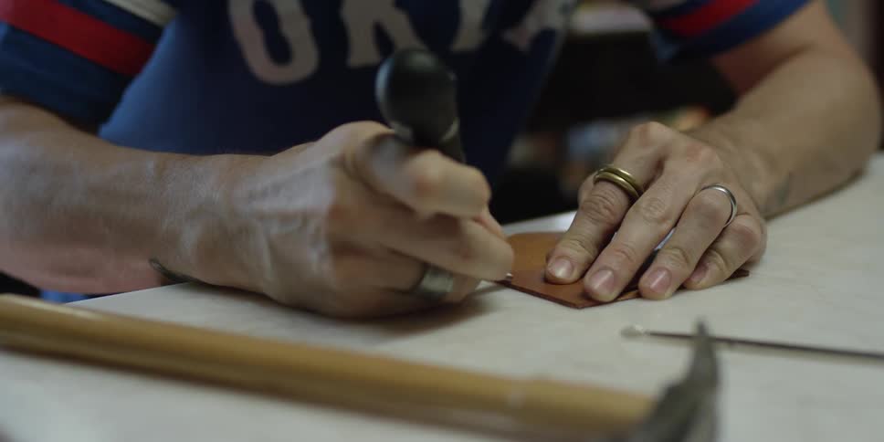A man is using a tool on leather