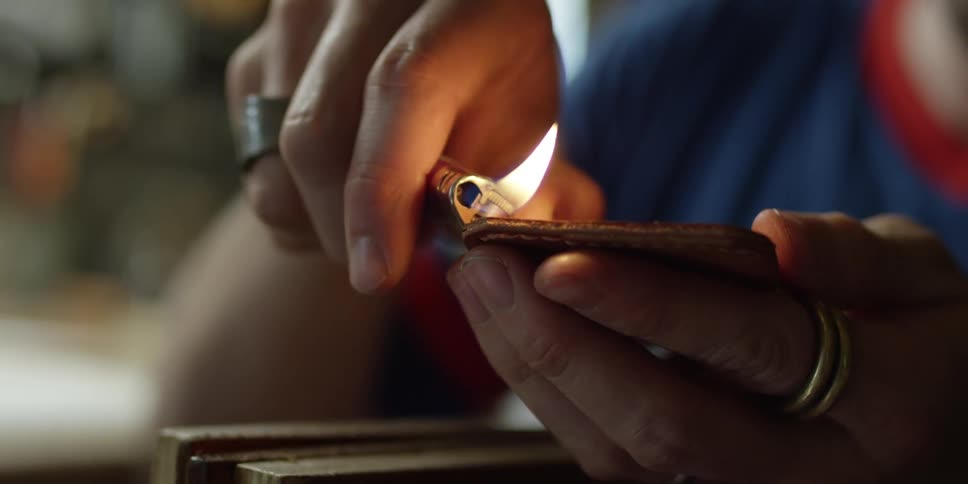 A person uses a lighter on an object