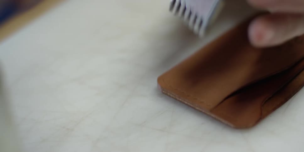A person punches holes into leather strips