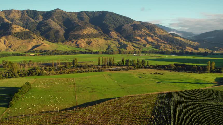 A farm sits below tall rolling hills