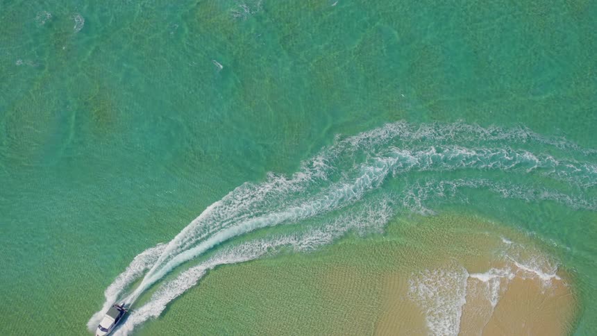 A boat is traveling through clear green ocean water near the shore