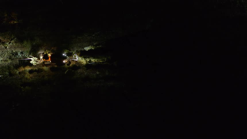 A tractor cultivates crops on a farm at night