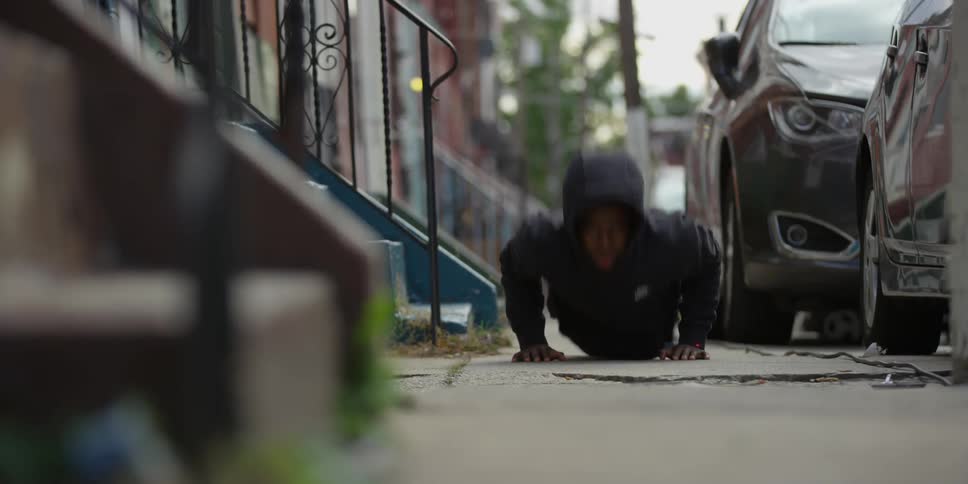 A man is doing pushups on a sidewalk