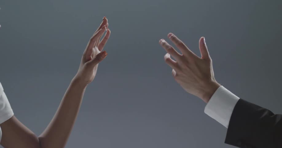 A man and woman hands and arms in a room with a wall in the background