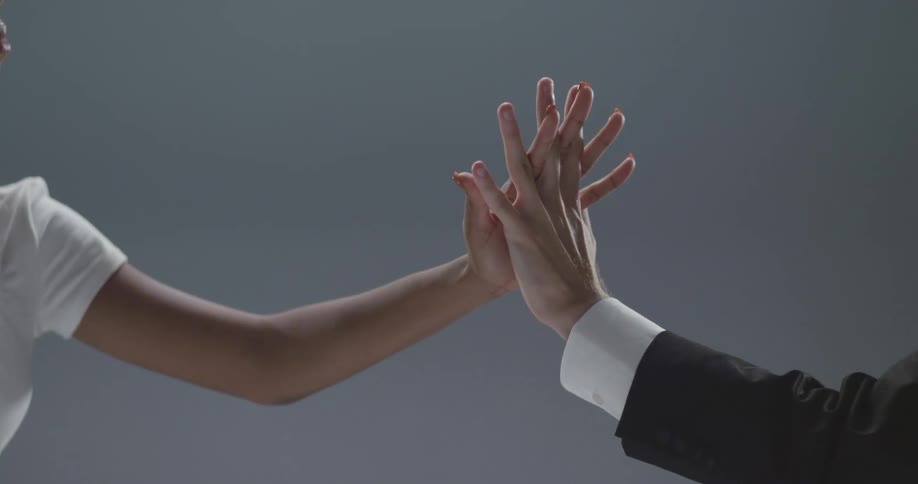 A man and a woman in a room holding hands with a wall in the background