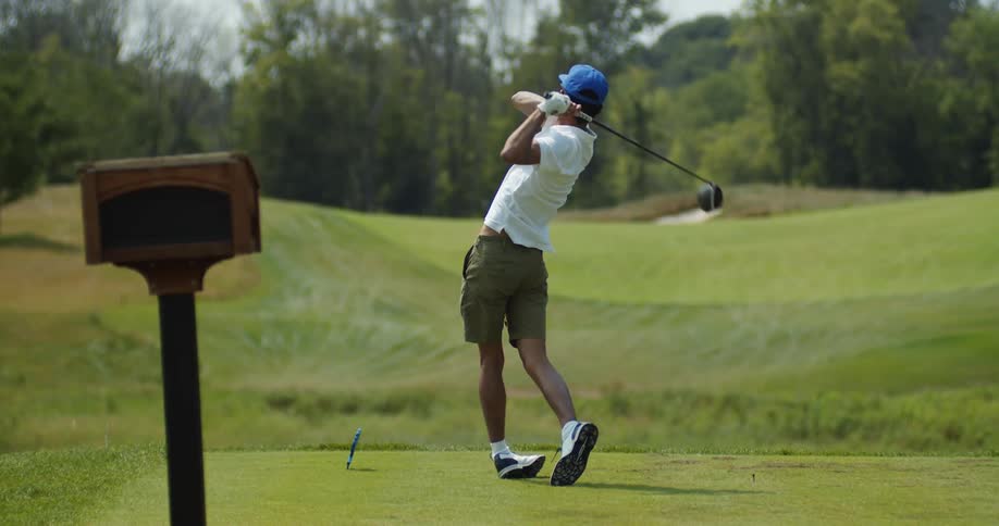 A man swings a golf club at a ball