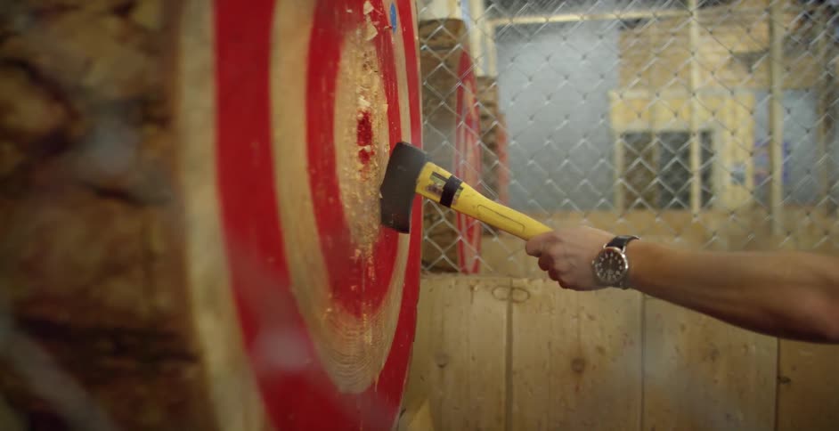 Man retrieving an ax stuck on a target inside an ax throwing range