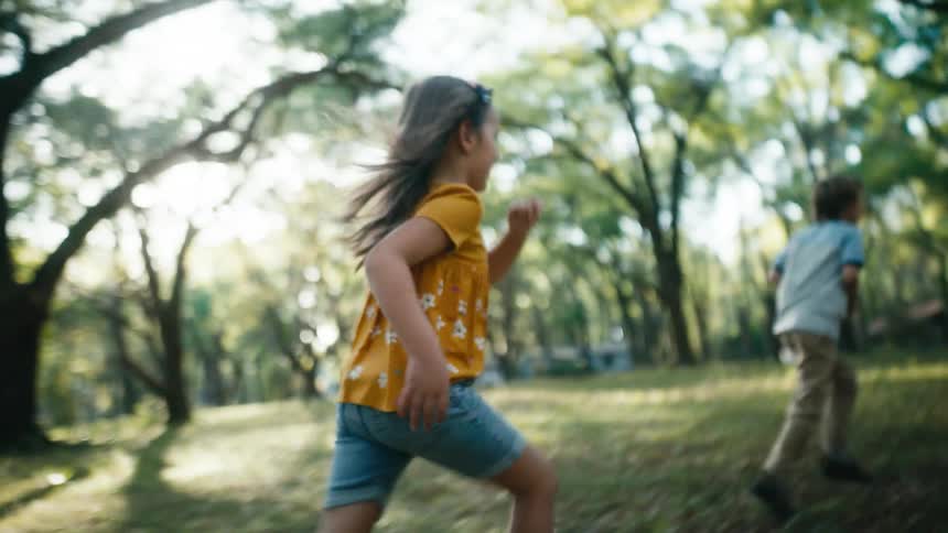 A young girl runs in a rural yard closer to a boy