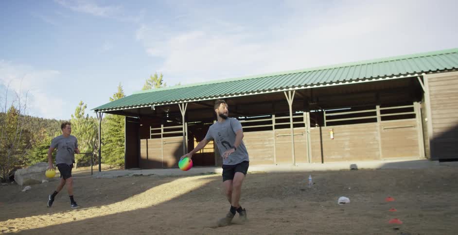 Two men are throwing dodge balls while playing