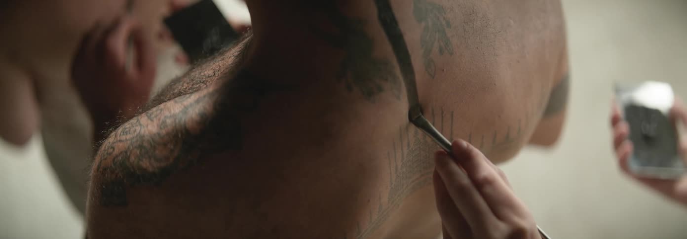 Group of people painting each others backs with henna ink using small brushes