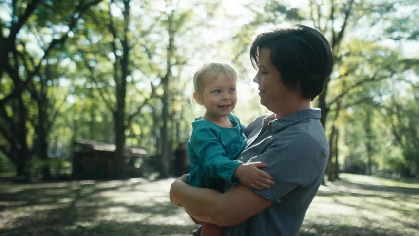 A mother holding her daughter outdoors