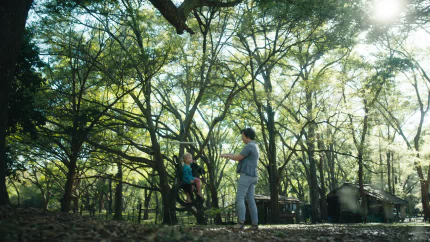 A woman is pushing a small girl on a tire swing