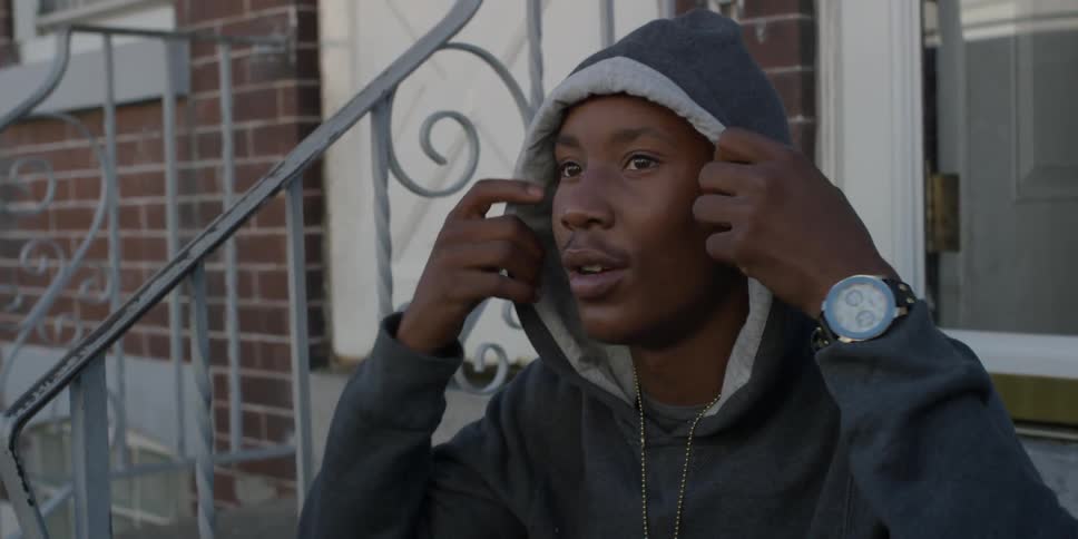 A man in a gray hoodie pulls up his hood
