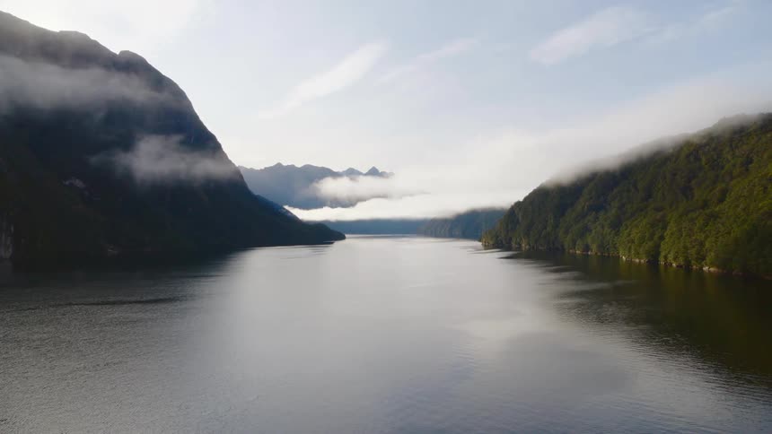 Fog moves over a lake between mountains under a cloud filled sky