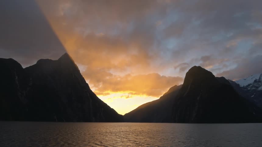 Lake with the sun setting between mountains in the distance