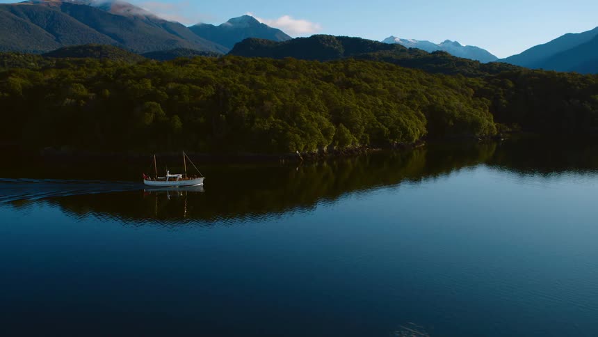 A boat sits in very still water in a lake in the mountains