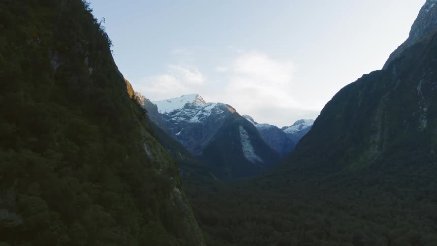 River flows between forested mountains leading to snow coveredmountain