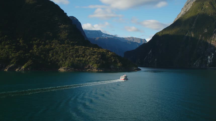 A ferry on a river with cliffs the sky and clouds in the background