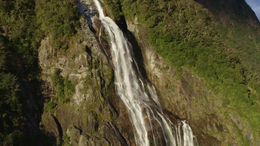 Aerial view of a waterfall flowing from the cliff side of a mountain in the morning