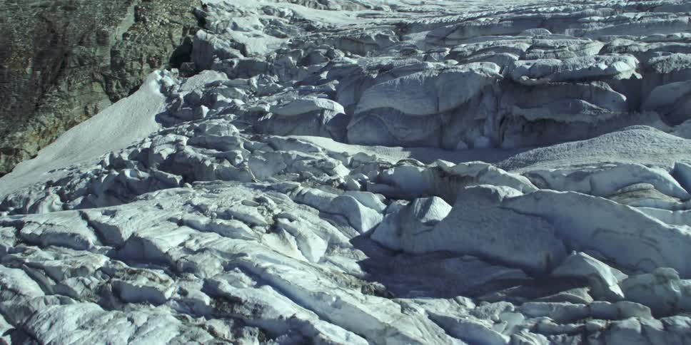 Snow and ice cover wide sloping plain bordering stone