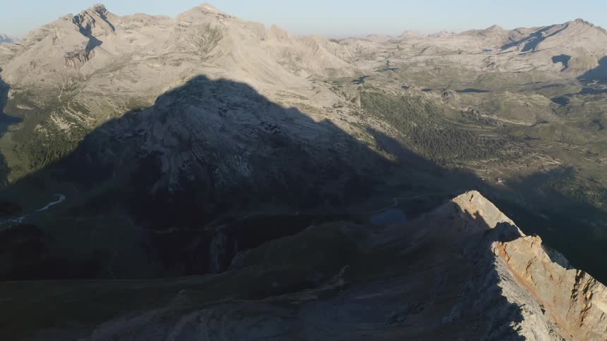 A tall mountain casts a shadow on lower sections of a mountain range
