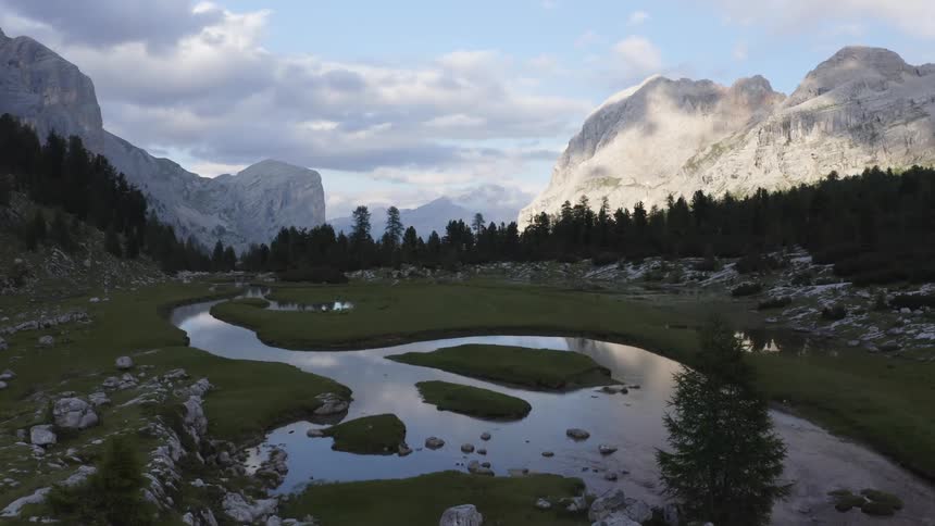 A river runs through a valley amongst large snowy mountains