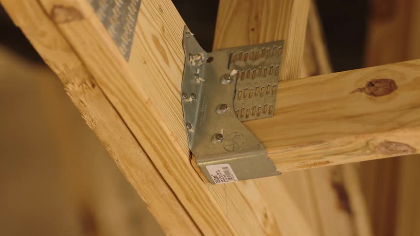 Metal fasteners and lumber are attached to hold a building framework