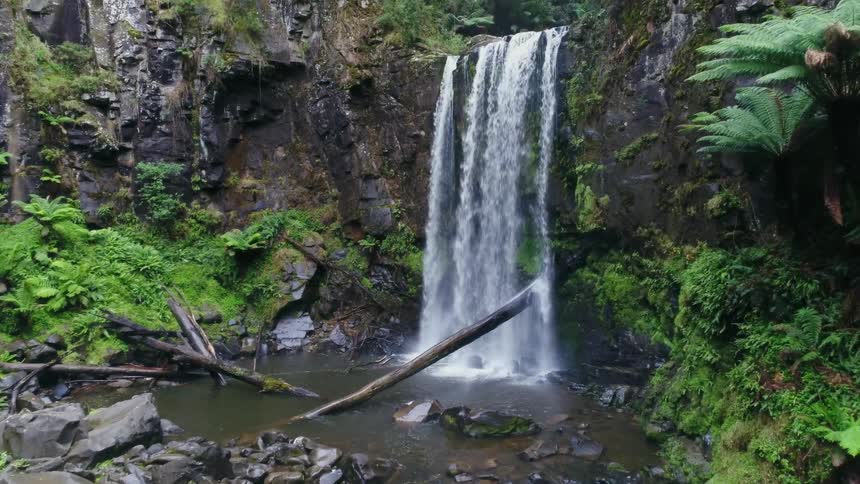 Waterfall at the side of a mountain flows into a stream below