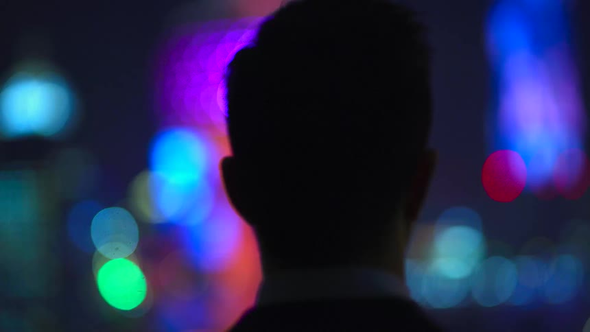 A silhouette of a persons head with lights in the background