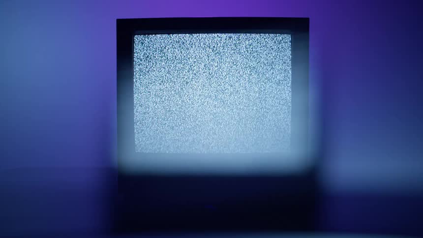 A television plays static in front of a blue wall that darkens and lightens