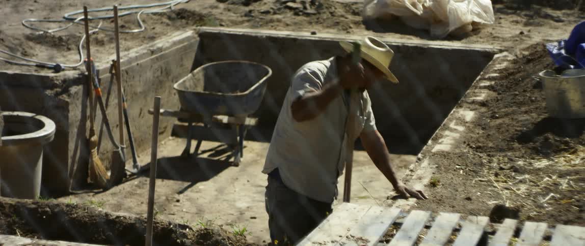 Man digs in a trench while standing in a foundation